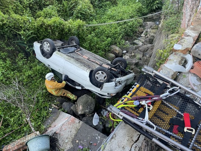 苗栗縣南庄鄉80歲駕車老翁11日上午載妻子返家，疑似倒車時誤把油門當煞車，車輛撞破自家圍牆後翻落山谷，警消合力吊掛救援，所幸2人均僅擦挫傷，意識清楚送醫無生命危險。（苗栗縣消防局提供）中央社記者管瑞平傳真  113年12月11日