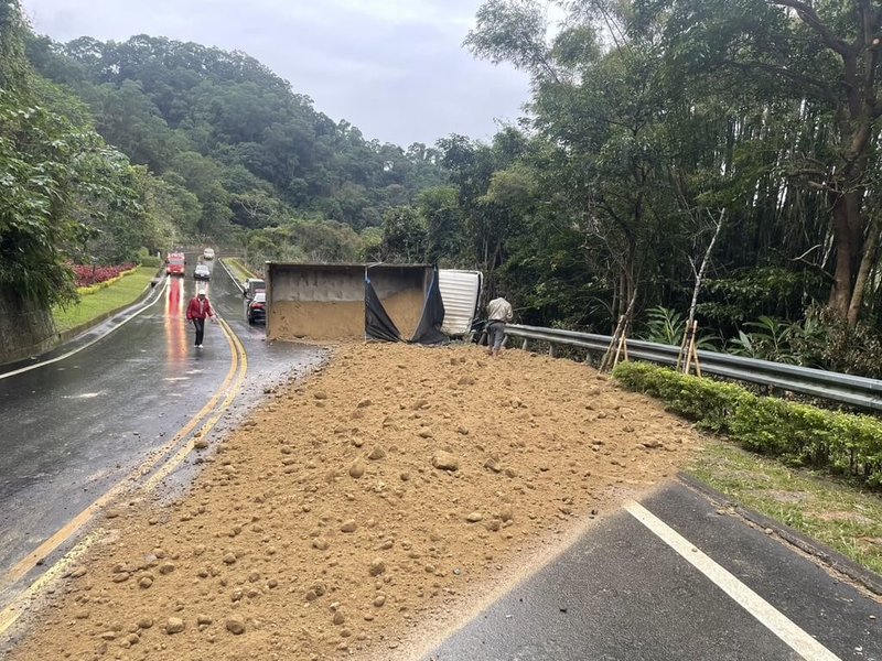 張姓男子23日駕駛貨車載運砂石欲送往砂石場，行經苗26線公館鄉北河村路段時，疑下坡路段煞車失靈加上天雨路滑，車輛失控翻覆，車斗砂石瞬間傾洩溢散路面；張男自行脫困，幸無生命危險。（民眾提供）中央社記者管瑞平傳真  113年12月23日