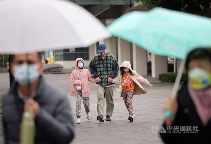 圖為台北市中山區街頭民眾戴上外套帽子保暖兼擋雨。（中央社檔案照片）