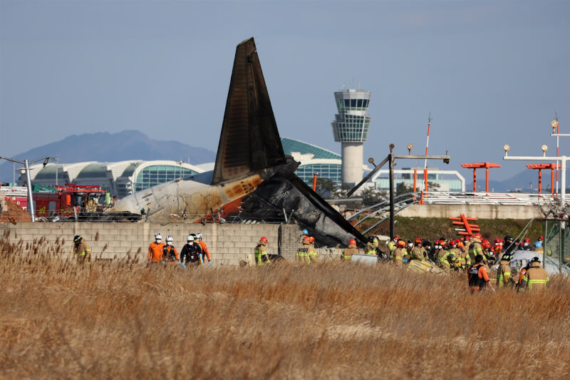 濟州航空一架班機降落韓國務安國際機場時,衝出跑道撞護欄起火,火勢撲滅後消防隊進行搜救。(韓聯社)