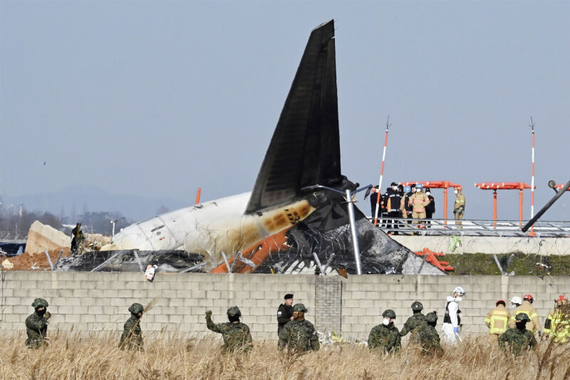 濟州航空班機29日降落韓國務安機場時失事衝出跑道撞護欄起火，全機含機組員共179死，僅2機組員生還。圖為事故發生後軍警與消防到場搜救。（共同社）