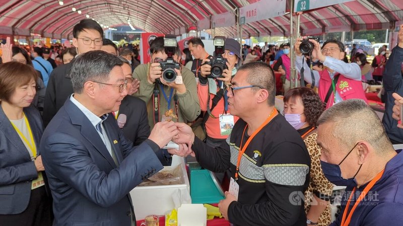 台灣更生保護會4日舉辦更生八十保護成果展暨年貨大街，行政院長卓榮泰（前左）試吃更生攤商「吳小胖」（前右2）的商品，並為對方加油打氣。中央社記者蘇木春台中攝  114年1月4日