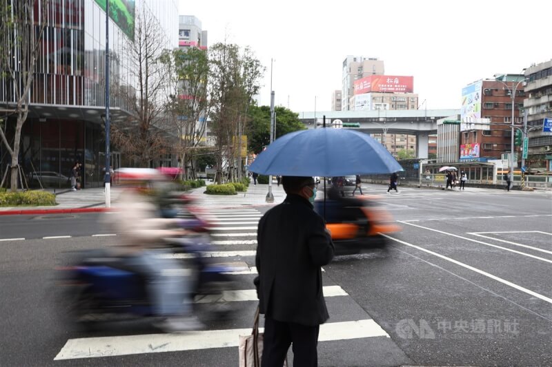 圖為台北市中正區民眾撐傘等紅綠燈。（中央社檔案照片）