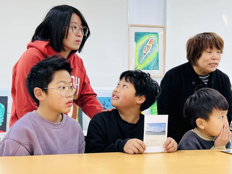 連江縣東莒國小與日本香川高松市立男木小中學校,17日舉辦線上交流會,東莒國小學生劉城伊(前中)向螢幕另一端介紹自己手繪的明信片,途中一度因為緊張望向背後的老師。(東莒國小提供)中央社記者潘欣彤傳真 114年1月17日