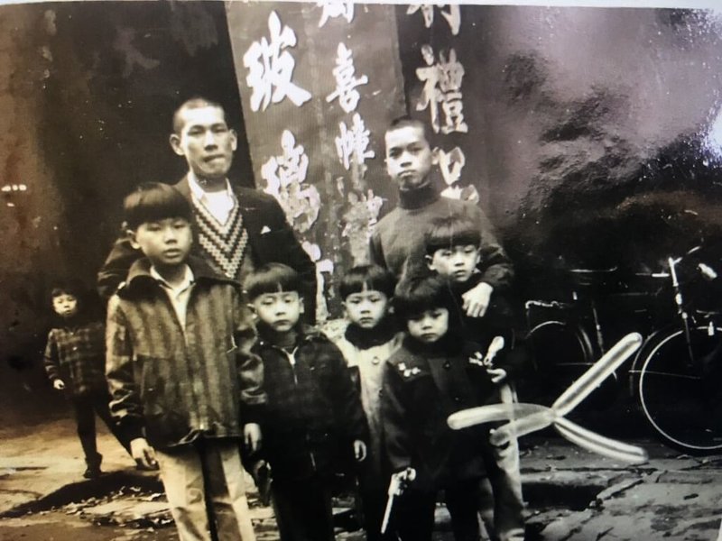基隆青年李俊廷在基隆市義二路承租店面開設手搖飲店,裝潢時,從鄰居得知承租的店面是祖父60年前租的老宅,希望能推廣義重町文化。圖為李俊廷的父親(前排左3)幼時在店門前與兄弟合影。(李俊廷提供)中央社記者王朝鈺傳真 114年2月2日
