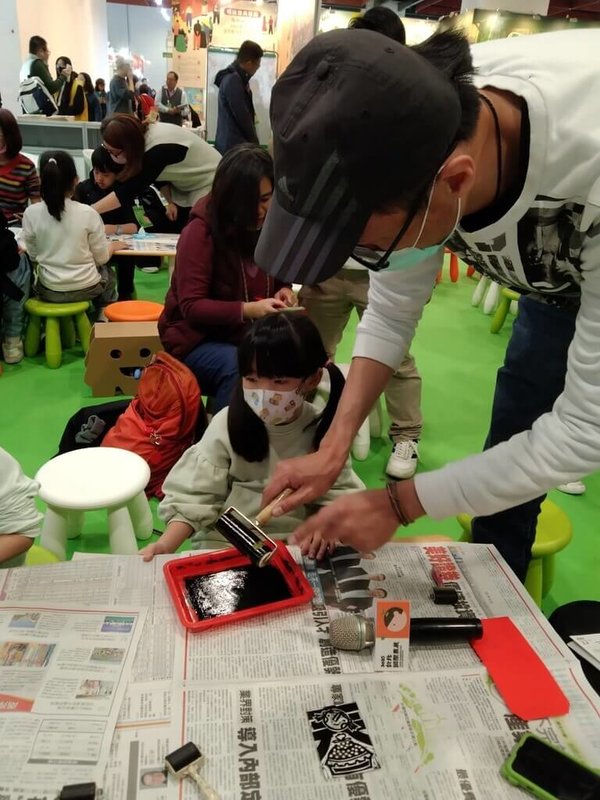 2025台北國際書展4日登場,信誼基金會於展期間推出多場親子故事遊戲活動,吸引親子族群參與。圖為繪本「米糕甜蜜蜜」作者江明恭(右)帶領小朋友體驗版畫的樂趣。(信誼基金會提供)中央社記者陳至中傳真 114年2月4日