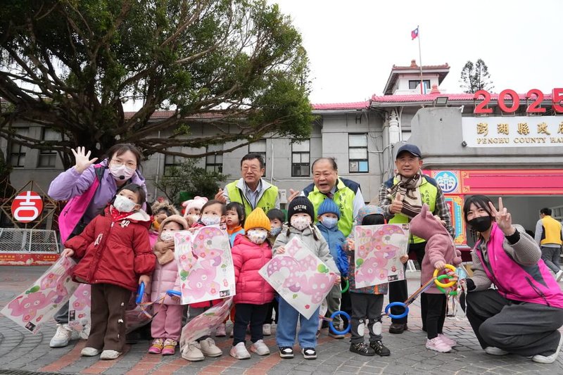 澎湖縣長陳光復（後中）、秘書長楊書舜（後左）與民政處長許啟川（後右）7日分別在縣府前廣場兩側發放「小花蛇」紙雕提燈，小朋友開心地拿著小提燈與陳光復等人合影。（澎湖縣政府提供）中央社  114年2月7日