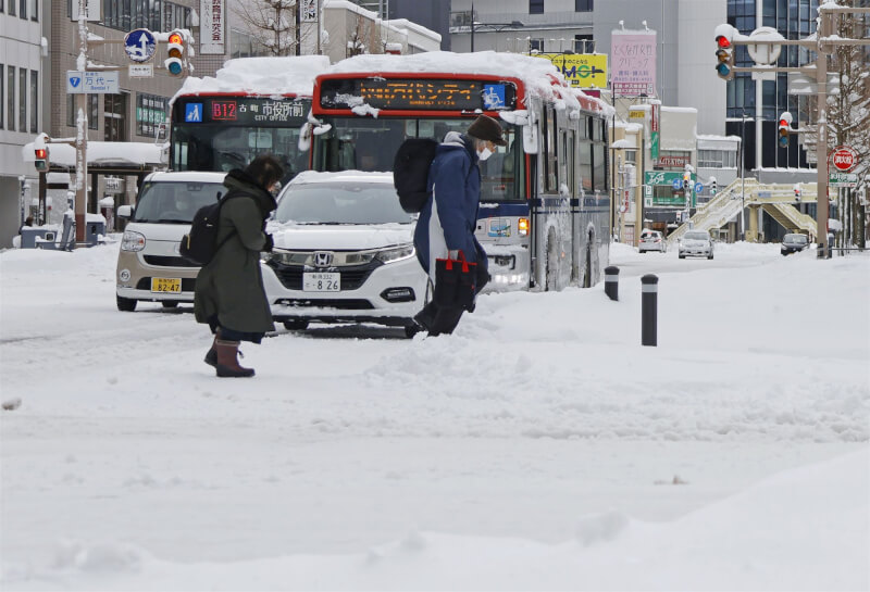 寒流襲日本，8日新潟市車輛和行人在大雪中前進。（共同社）