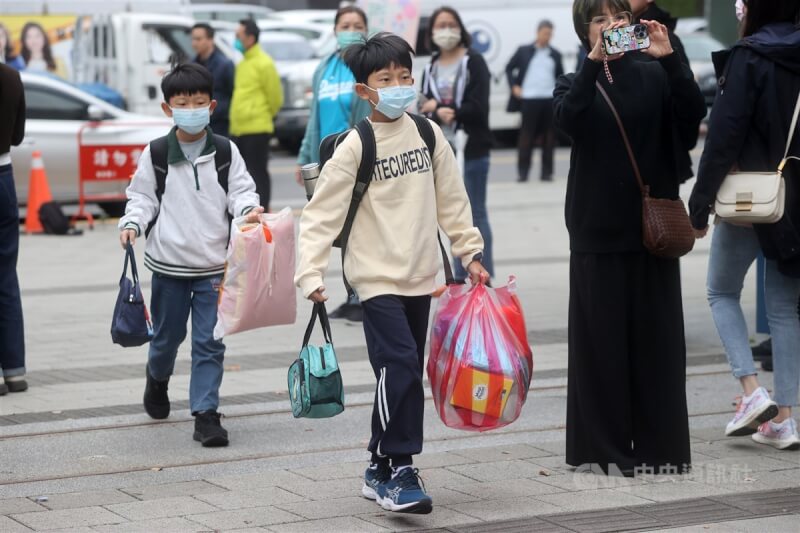 台北市的國小學生提著學用品進入校園。（中央社檔案照片）