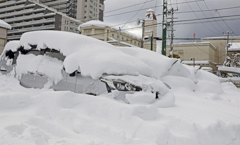 日本多地持續受到本季入冬最強寒流影響而降下大雪，8日新潟市車輛被大雪覆蓋。（共同社）