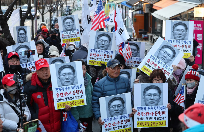 反對彈劾韓國總統尹錫悅的民眾17日聚集在憲法法院代理院長文炯培住家附近，手舉標語抗議。（韓聯社）