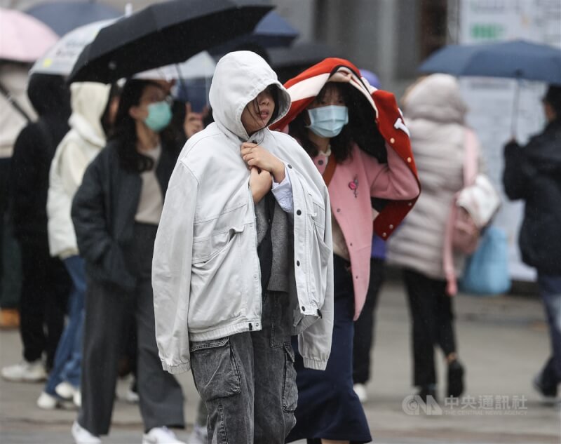 21日清晨起鋒面通過與東北季風增強，北部、東北部轉涼，且有局部短暫雨。圖為台北市中正區民眾搭起外套避雨。（中央社檔案照片）