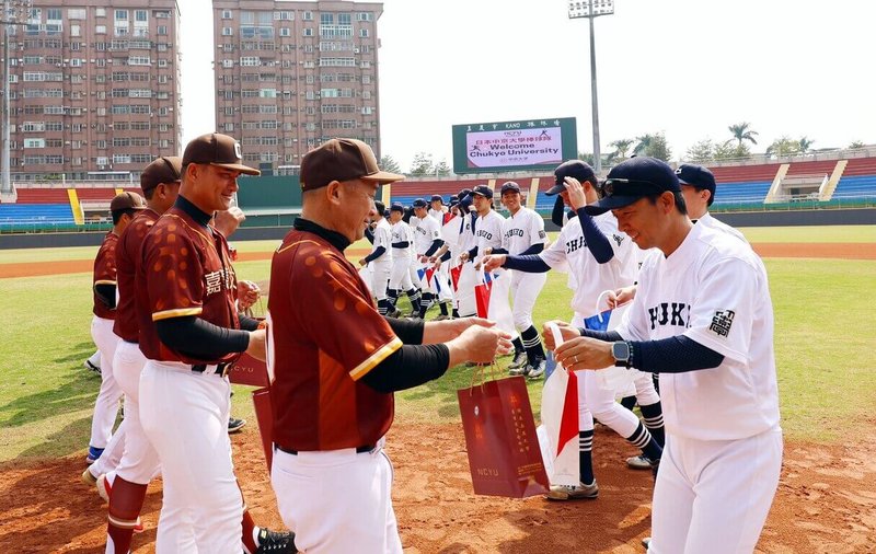 嘉義大學（紅衣者）與日本中京大學棒球隊21日在嘉義市立棒球場展開交流賽，重現1931年甲子園冠軍賽KANO決戰戲碼，雙方球員並互相交換禮品。（嘉義大學提供）中央社記者黃國芳傳真 114年2月21日