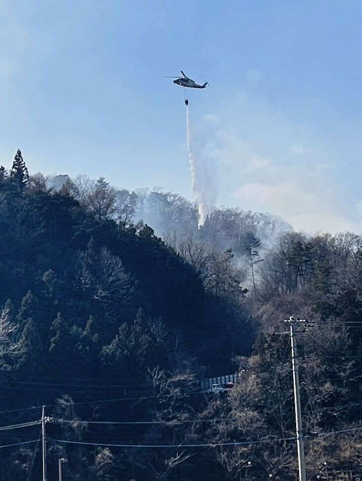 日本山梨縣大月市森林火勢蔓延，2月28日出動直升機灑水滅火。（共同社）