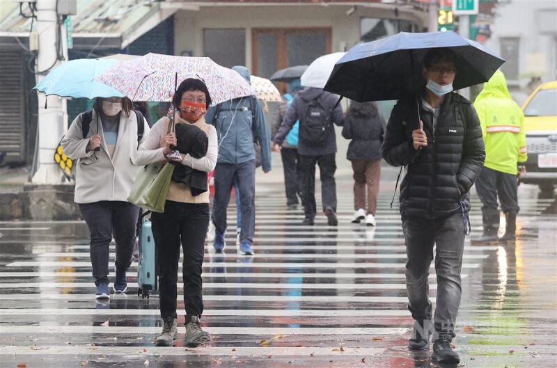 氣象署表示，由於鋒面與東北季風，各地須留意強降雨與雷擊。圖為台北市民眾撐傘過馬路。（中央社檔案照片）