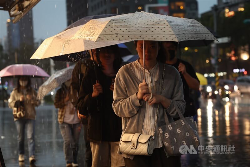 圖為新北市板橋區傍晚降下大雨,街上行人撐傘走避。(中央社檔案照片)