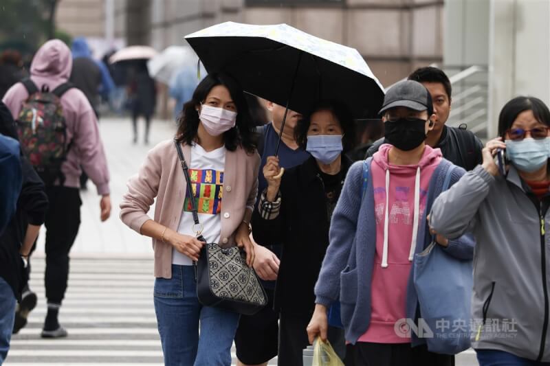 氣象署表示，10日各地氣溫逐漸回升，局部地區偶有零星短暫雨。圖為台北市信義區，民眾撐傘過馬路。（中央社檔案照片）