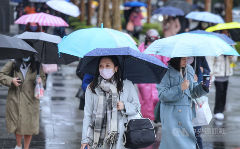 圖為台北市內湖區民眾戴圍巾保暖、撐傘遮擋雨勢。（中央社檔案照片）