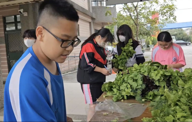 高雄市燕巢國中善用校園空間建置魚菜共生系統，校方13日說明，學生上學期運用自種蔬菜製作漢堡，親身體驗從產地到餐桌過程；這學期則挑戰農產行銷，學習如何自產自銷推廣至社區，深化食農教育實踐經驗。（燕巢國中提供）中央社記者林巧璉傳真  114年3月13日