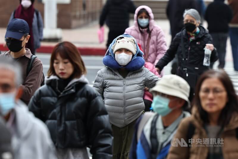 圖為台北市中正區民眾穿著保暖衣物並戴上毛帽、口罩保暖。（中央社檔案照片）