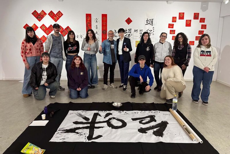 華梵大學美術系助理教授楊侖(後排右5)帶著筆墨紙硯等教材和「蚵仔煎」口味薯片,書法藝術與真實五感體驗結合,帶領西班牙學生舉辦台味書法集體創作。(華梵提供)中央社記者許秩維傳真 114年3月24日