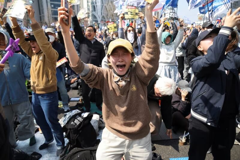 韓國憲法法院前聚集的民眾得知總統尹錫悅遭彈劾下台，興奮地高舉雙手大喊。（路透社）