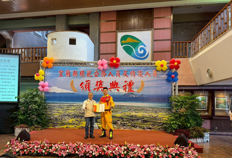 宜蘭縣模範公務人員及績優人員頒獎典禮16日在縣府縣民大廳舉行,由代理縣長林茂盛(左)頒獎表揚25名獲獎者,其中一人為消防局蘇澳分隊基層消防隊員呂劭宥(右)。(宜蘭縣消防局提供)中央社記者王朝鈺傳真 114年4月16日