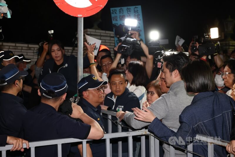 台北地檢署偵辦不實連署案,國民黨中央17日晚間號召黨公職與群眾到北檢外聚集抗議表訴求,台北市長蔣萬安(前右2)抵達時一度被卡在柵欄外,與警方溝通交涉。中央社記者王騰毅攝 114年4月17日