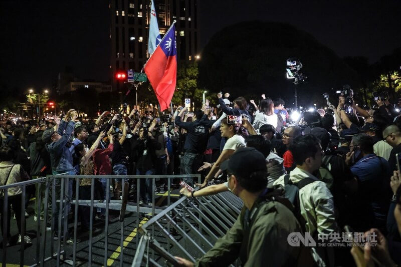 國民黨黨公職及支持者17日晚間響應黨主席朱立倫號召,踏過警方架設的圍欄前往北檢前抗議,現場揮舞中華民國國旗。中央社記者趙世勳攝 114年4月17日