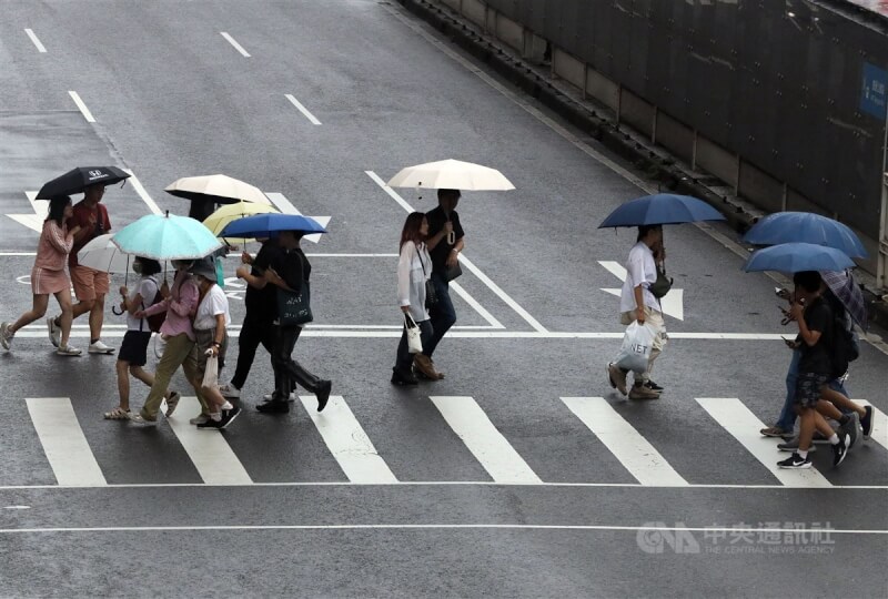 氣象署表示,25日中部以北、宜蘭、花蓮及金門馬祖有局部較大雨勢。圖為台北市民眾撐傘穿越馬路。(中央社檔案照片)