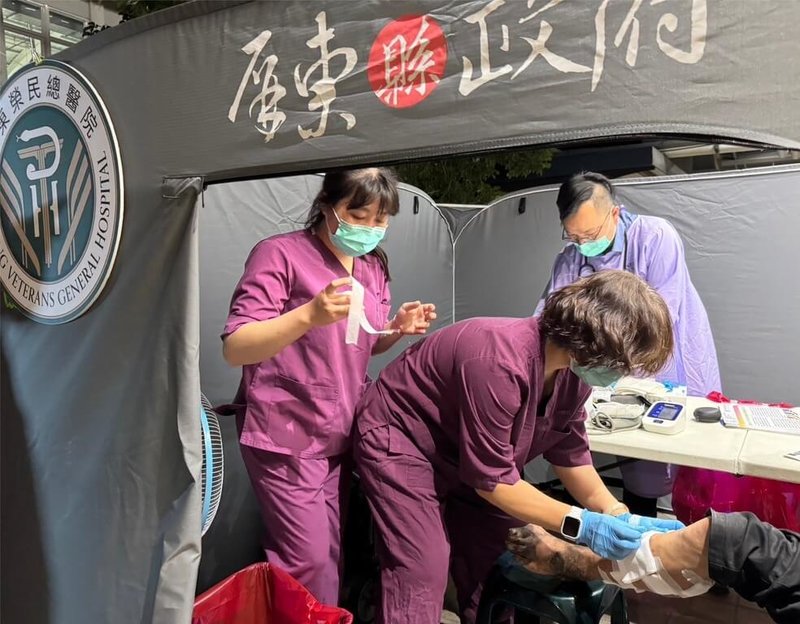 屏東縣政府結合屏東榮民總醫院等團體，為街友提供醫療外展服務，首場看診29日晚間在屏東火車站登場，護理師為看診民眾包紮。（屏東縣政府社會處提供）中央社記者黃郁菁傳真  114年4月30日