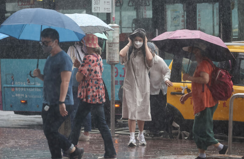 圖為台北車站周邊有民眾未攜帶雨具,以衣物擋雨。(中央社檔案照片)