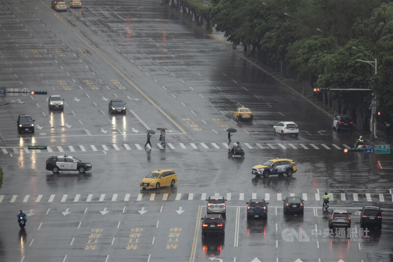 圖為台北市中正區午後天色昏暗、雨勢不斷,路上行人撐傘過馬路。(中央社檔案照片)