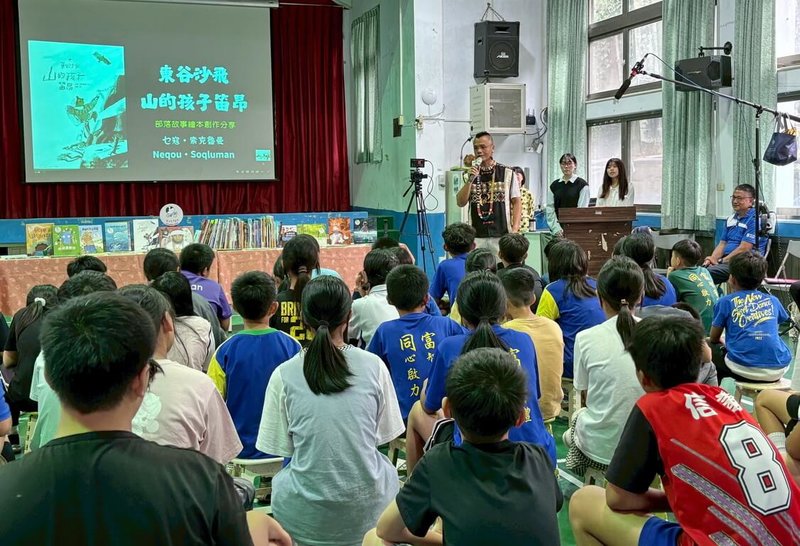 國立台灣圖書館9日邀請布農族作家乜寇.索克魯曼(後持麥克風者)到南投縣信義鄉同富國小與學童分享新作,引導學生從部落語境認識自然、文化。(國台圖提供)中央社記者黃旭昇新北市傳真 114年5月10日