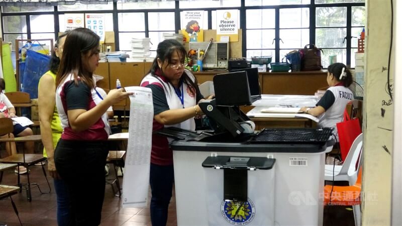菲律賓12日舉行期中選舉,改選參議院24席中的12席,並選出300多名眾議員,以及各省市鎮地方首長和地方議員。圖為馬尼拉一投票所內,選務人員協助選民將填好的選票投入計票機。中央社記者林行健馬尼拉攝 114年5月12日