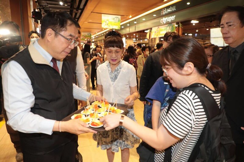 台南市金鑽鳳梨、木瓜與洋香瓜等農產水果,即日起在北台灣8家遠東City Super分店上架銷售。圖為台南市長黃偉哲(前左)14日在新北市板橋大遠百端送水果供民眾試吃。(台南市政府提供)中央社記者張榮祥台南傳真 114年5月14日