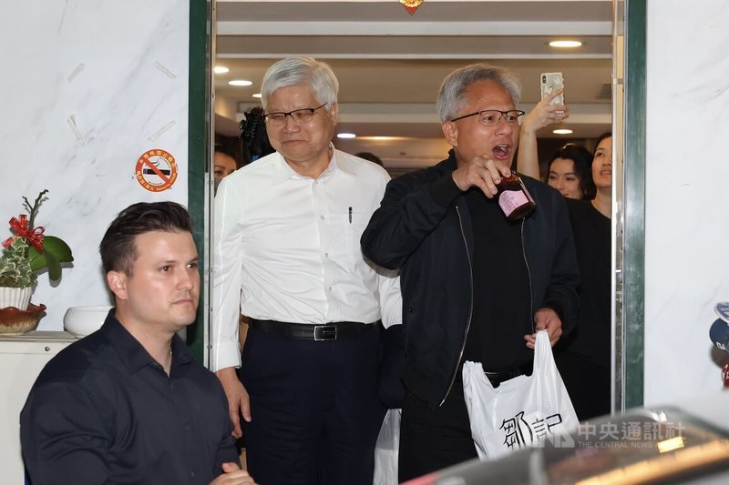輝達(NVIDIA)執行長黃仁勳(右)16日抵台後,晚間率先與台積電董事長暨總裁魏哲家(左2)在台北共進晚餐,離開時黃仁勳特別秀出他在餐廳購買的產品。中央社記者翁睿坤攝 114年5月16日