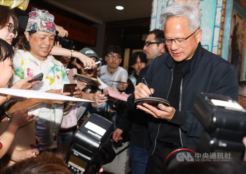 輝達執行長黃仁勳(右)17日傍晚在台北宴請供應鏈夥伴,吸引大批媒體、粉絲在店外守候,黃仁勳席間數度走出餐廳親切為粉絲簽名。(中央社檔案照片)