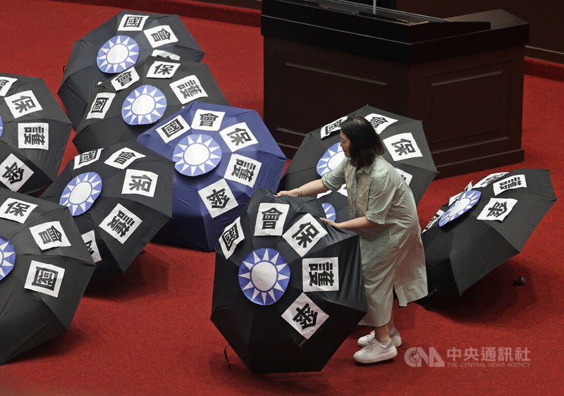 立法院會20日擬處理國民黨立法院黨團所提本會期延會至7月31日、反戒嚴公投等案,民進黨立法院黨團在議場擺放「國會保護傘」字樣與國民黨徽的雨傘,批評藍營是因為怕罷免,意圖延長會期。中央社記者裴禛攝 114年5月20日