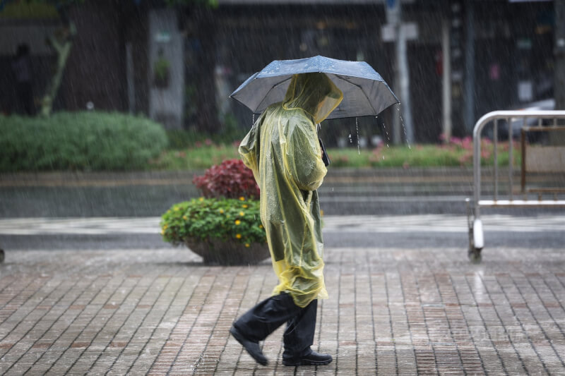 圖為台北市中正區街頭民眾穿起雨衣搭配撐傘阻擋雨勢。(中央社檔案照片)