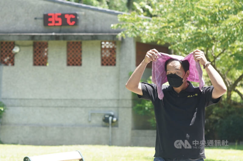 圖為民眾在大安森林公園以毛巾遮陽。(中央社檔案照片)