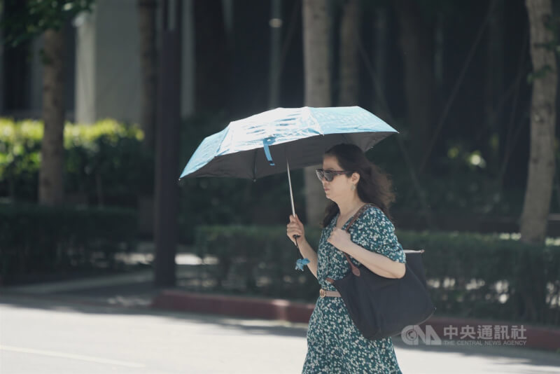 圖為民眾22日走在台北市中正區街頭撐傘遮陽。(中央社檔案照片)