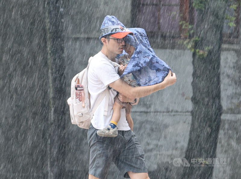 中央氣象署22日發布大雨特報,並針對桃園市、新竹縣跟宜蘭縣發布大雷雨即時訊息。圖為民眾抱著小孩前往躲雨。(中央社檔案照片)