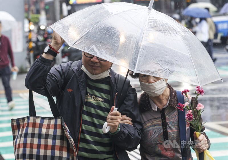 圖為新北市民眾過馬路撐傘擋雨。(中央社檔案照片)