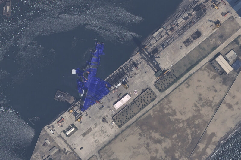 北韓一艘軍艦21日下水發生意外。22日衛星影像顯示,軍艦上覆蓋藍色防水布,側翻在清津造船廠水中。(Airbus DS via 美聯社)