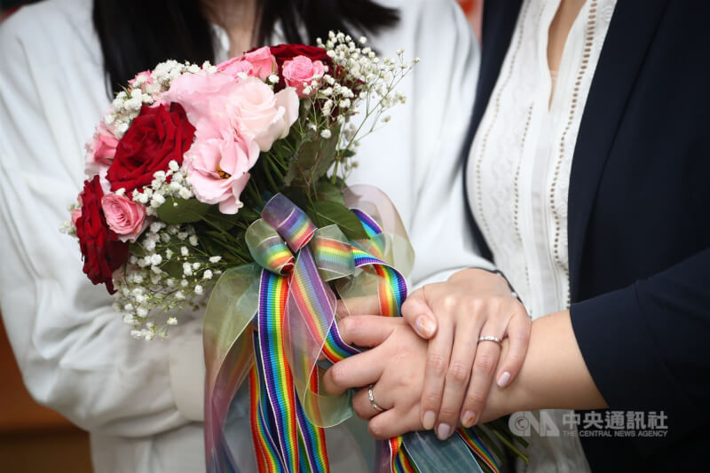 同性伴侶拿著綁有彩虹緞帶捧花登記結婚。(中央社檔案照片)