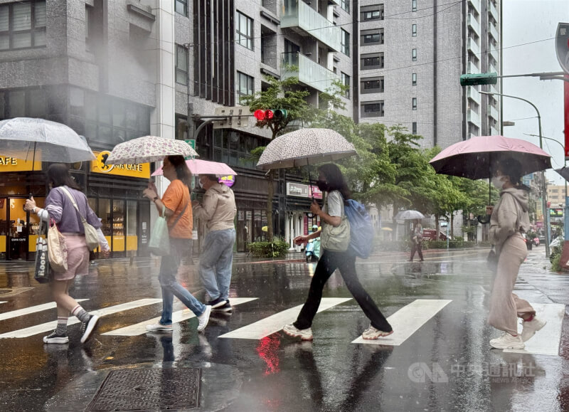 圖為台北市內湖區民眾撐傘過馬路。(中央社檔案照片)