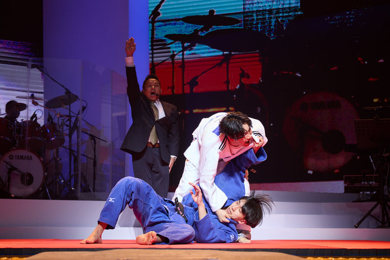 金曲歌王蕭煌奇(中白衣者)「朋友你現在好嗎」演唱會5月31日在台北流行音樂中心落幕,安可演出時,他特別換上柔道服,驚喜帶來柔道過招橋段,舞台上還配有裁判,嗨翻全場。(華納音樂X寬宏藝術提供) 中央社記者陳怡璇傳真 114年6月1日