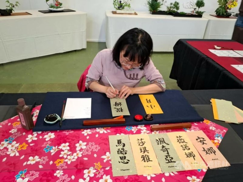 台灣書法家游蕙嘉以客家花布裝飾書法展示區,在花道展區揮毫,增加台灣元素。中央社記者郭芳君蘇黎世攝 114年6月2日