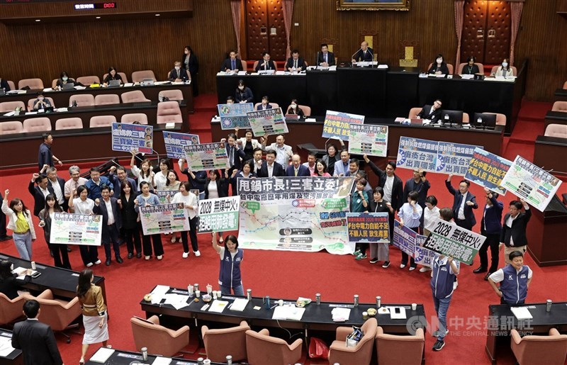 圖為立法院通過決議2028年完成無煤中火,藍綠兩黨立委在表決時舉牌,各自表達訴求。(中央社檔案照片)